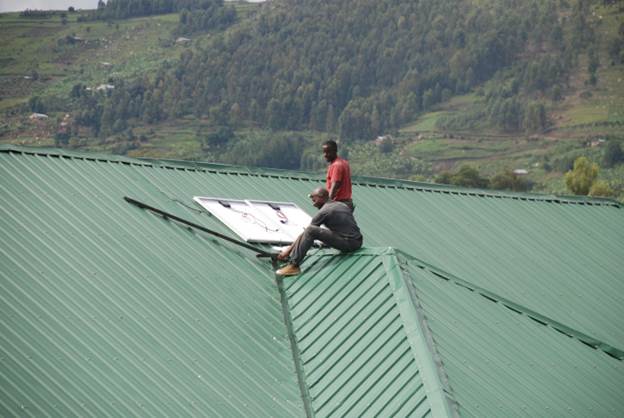 Solar Light for Africa contractor Timothy and technician Charles installing solar panels on the new ward at Nyakishenyi Catholic Health Centre